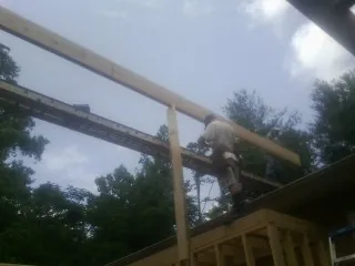 Carpenter setting a ridge beam over a new addition frame — Ice Dam Removal by Roofing Brothers in Bullock