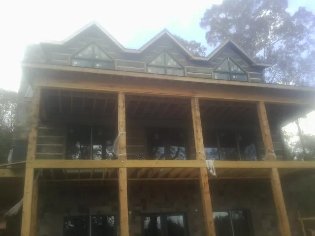 Dormers and porch framing on a large log home under construction — Roof Coating work by our crew in Bullock