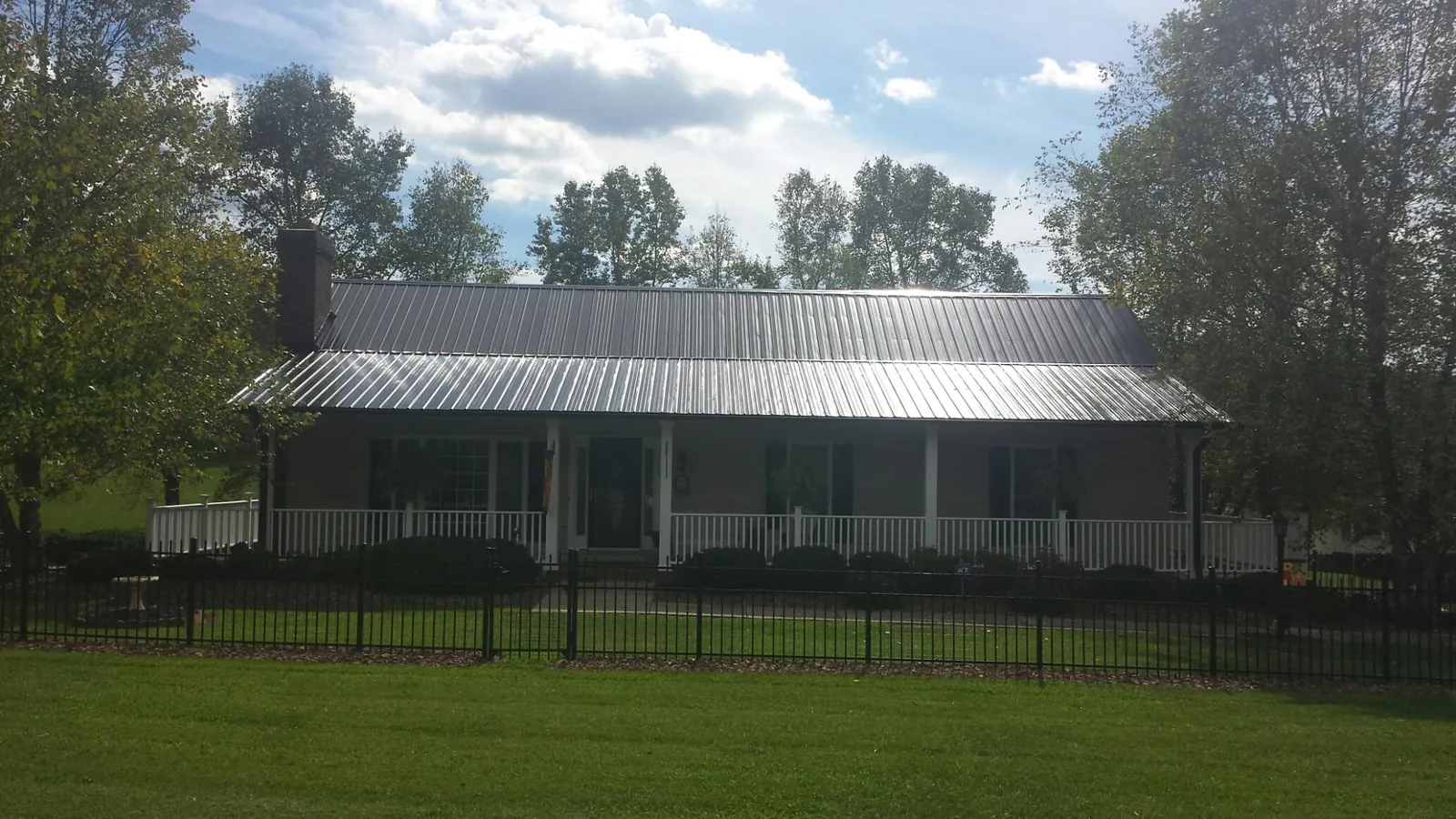 Gray metal roof on a brick ranch with a full width front porch — Gutter Guard Installation work by our crew in Bullock