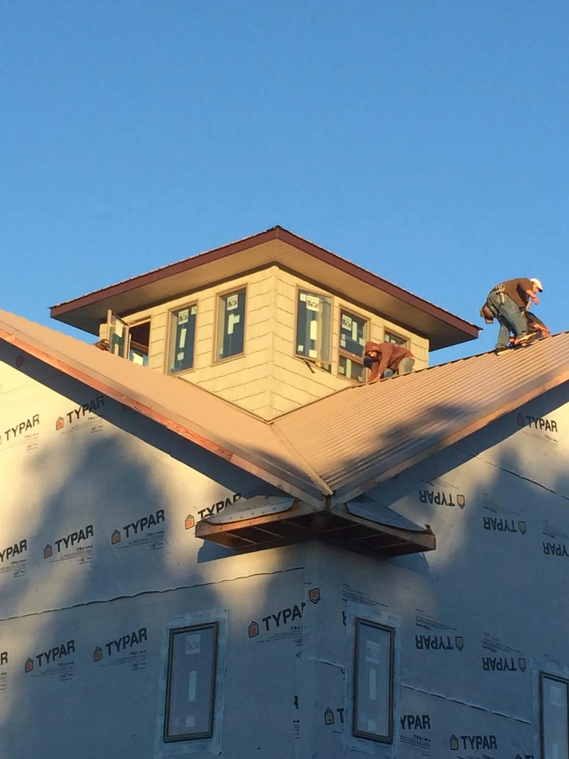 Roofers working around a rooftop cupola on a new metal roof at sunset — Roof Waterproofing in Bullock by Roofing Brothers